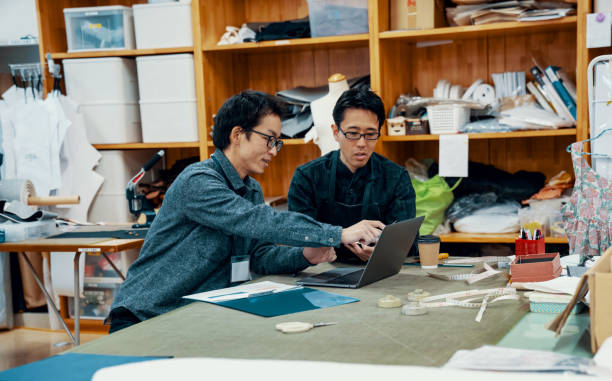 istock Mid adult design professionals working at a computer in a textile factory 1138387911