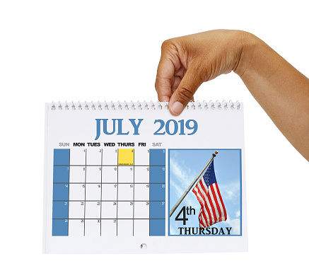 Hand holding July 2019 Calendar with American flag and Independence Day highlighted white background