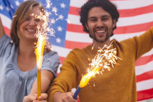 istock Caucasian couple playing with fire cracker while holding american flag 1138388017