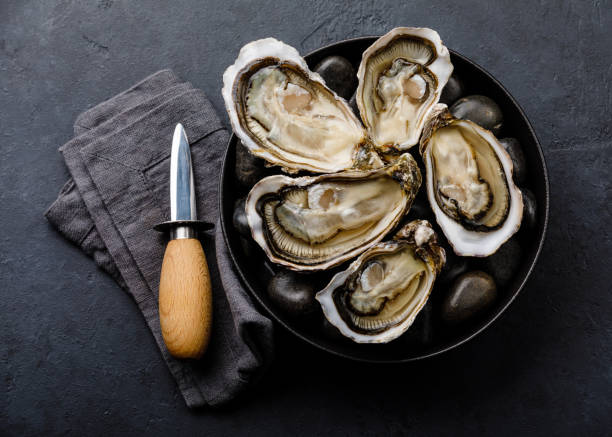 新鮮なカキとレモンとナイフ、暗い背景に石 - prepared oysters prepared shellfish shucked seafood ストックフォトと画像