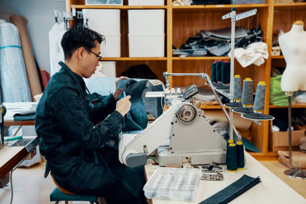 istock Mid adult tailor working at a sewing machine in his design studio 1138388028