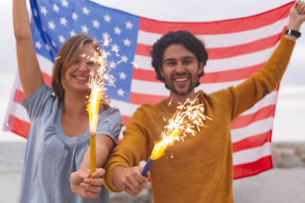 istock Caucasian couple playing with fire cracker while holding american flag 1138388046