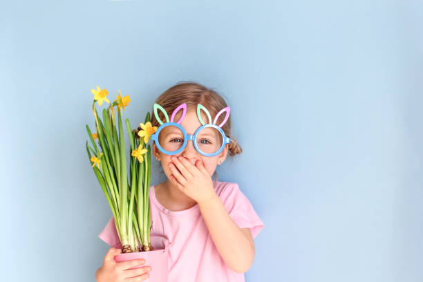 ute маленький ребенок носить кролика уши очки и проведение цветы в день пасхи. - child easter flower little girls стоковые фото и изображения