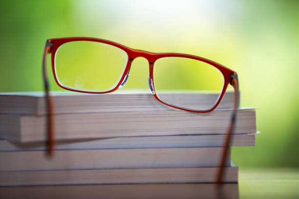 occhiali arancioni con libri su tavolo in legno, sfondo giardino bokeh, close up & macro shot, messa a fuoco selettiva, concetto di cancelleria - arts symbols studio shot selective focus entertainment foto e immagini stock