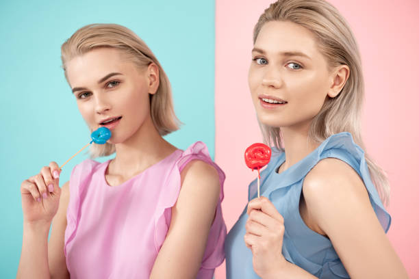 istock Blonde females consuming sweets on stick 1138393512