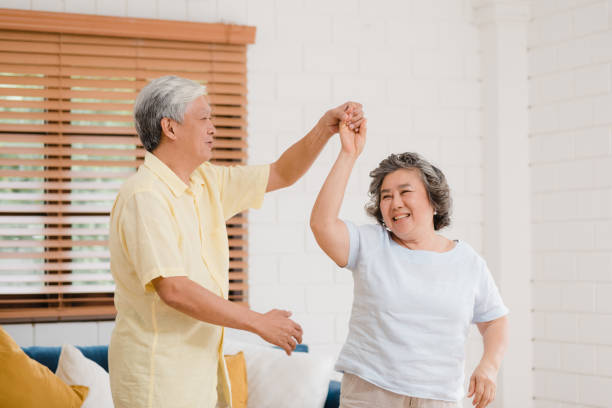 asian elderly couple dancing together while listen to music in living room at home, sweet couple enjoy love moment while having fun when relaxed at home. lifestyle senior family relax at home concept. - grandmother action senior adult grandparent imagens e fotografias de stock