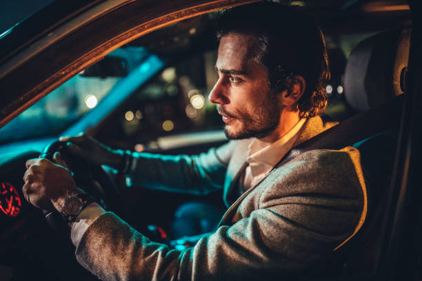 caballero conduciendo un coche en la ciudad por la noche - car speed lifestyles night fotografías e imágenes de stock