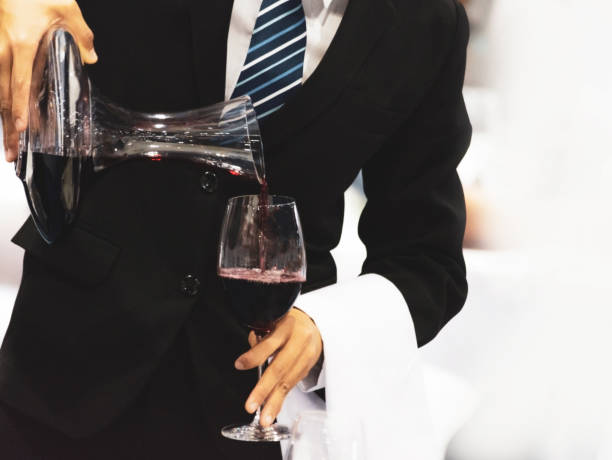 istock Waiter pouring red wine in a glass at a restaurant table 1138396018