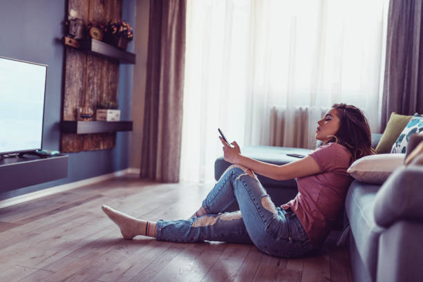 istock Cute Female Sitting On Floor And Watching Television 1138396762