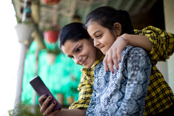 istock Mother and daughter using mobile phone at porch 1138398936