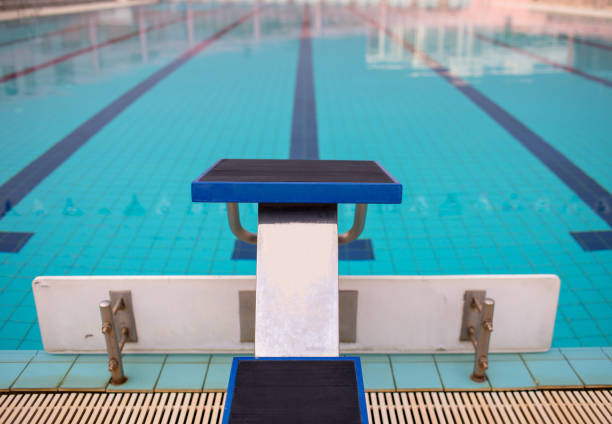 Starting blocks in row by the swimming pool, selective focus. Jump platform for swimming in swimming pool and grandstand background. Swimming pool with starting blocks. Sport facility.