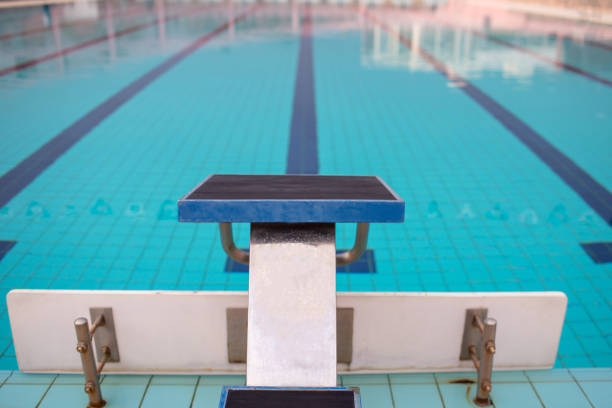 Starting blocks in row by the swimming pool, selective focus. Jump platform for swimming in swimming pool and grandstand background. Swimming pool with starting blocks. Sport facility.
