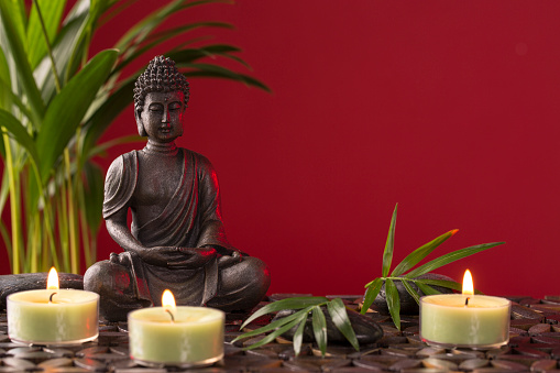 Buddha statue and  candles on a red background