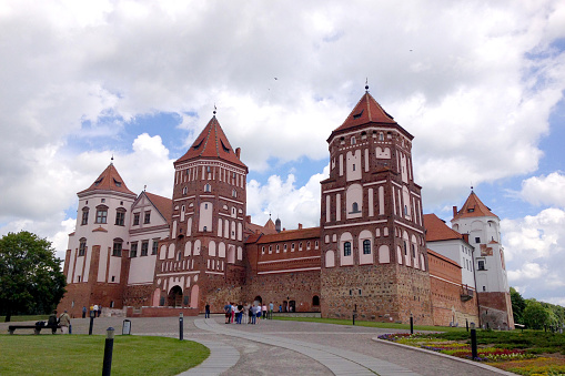 Mir, Belarus - June 13, 2014: Mir Castle on the background of blue sky with clouds summer day, Belarus. Tourists walk around the castle