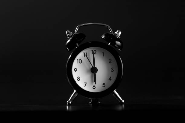 istock Black old style alarm clock isolated on black background. close-up 1138402609