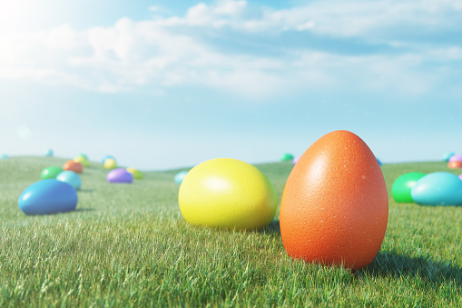 Colorful eggs in a meadow on a sunny day against the blue sky. Multicolored painted easter eggs on grass, lawn. Concept easter eggs hunt in sunday. Easter symbol holiday in April, 3D illustration