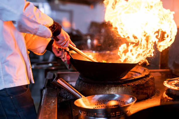 istock Chef cooking with flame in a frying pan on a kitchen stove 1138404450