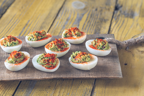 Guacamole and bacon deviled eggs on cutting board