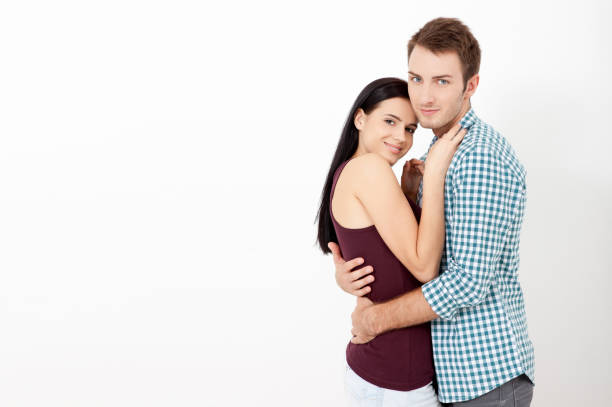 istock Happy couple embracing and looking camera on white background 1138411005