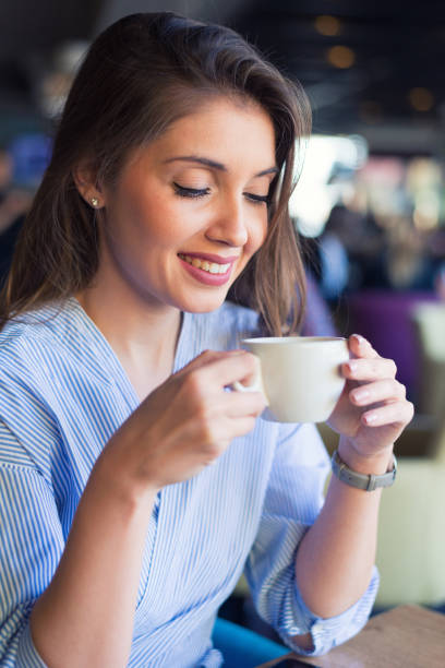istock Smiling young woman drinking coffee in the cafe 1138412378