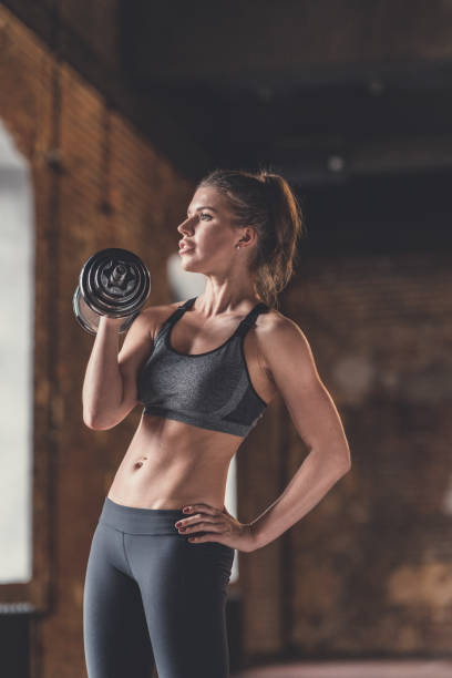 istock Athletic young girl with dumbbells indoors 1138413205