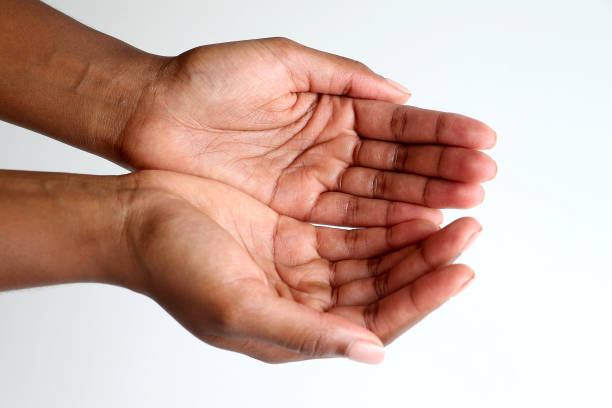 Black man's hands extended, palms in sharp focus, black background. Color image conveys the ideas of supplication, worship, welcome or reaching.