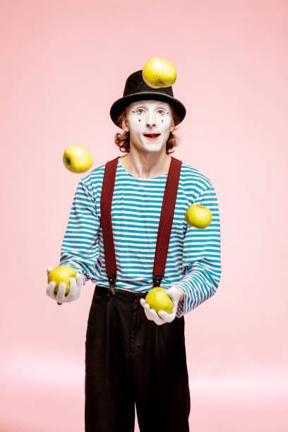 pantomime jongleren met appels op de roze achtergrond - jongleren stockfoto's en -beelden