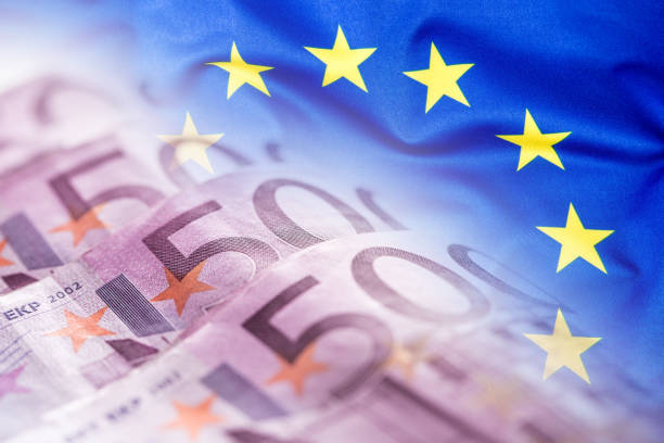 bandeira de ondulação colorida da união européia em um euro-fundo do dinheiro. - european union coin european union currency euro symbol coin - fotografias e filmes do acervo