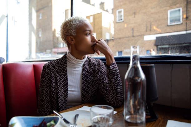 Pensive woman sitting by herself in a restaurant at lunch break Pensive woman sitting by herself in a restaurant at lunch break english cuisine stock pictures, royalty-free photos & images