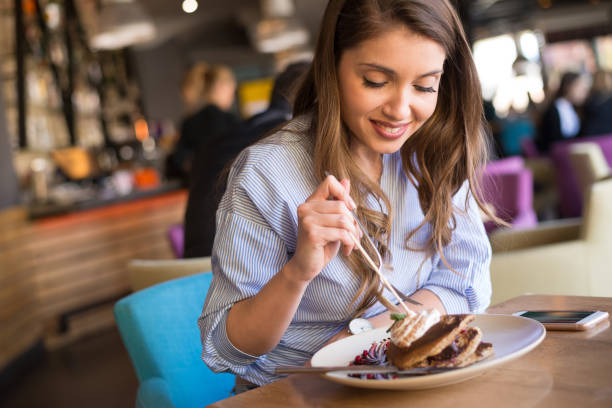 Young woman eating pancakes in the restaurant stock photo