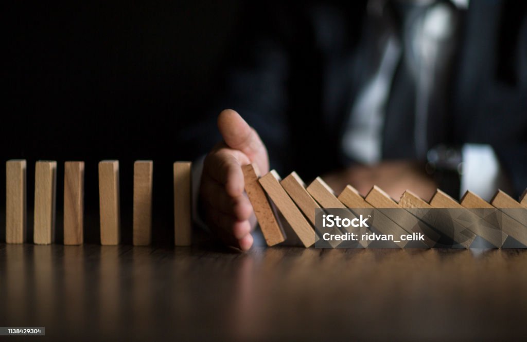 Businessman Stop Domino Effect. Risk Management and Insurance Concept Risk Management Stock Photo