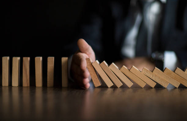 Businessman Stop Domino Effect. Risk Management and Insurance Concept Businessman Stop Domino Effect. Risk Management and Insurance Concept insurance protection stock pictures, royalty-free photos & images