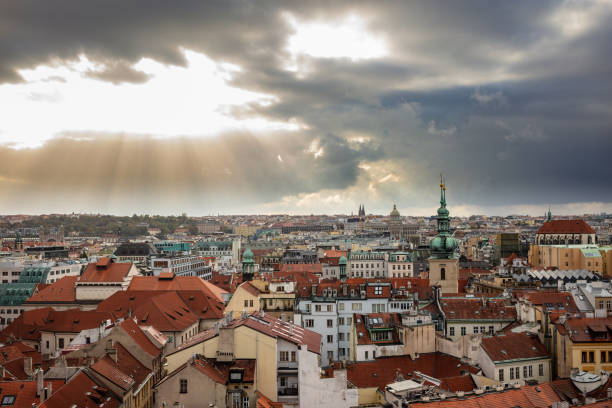 istock Panoramic view of Prague. Traditional red rooftops under sunbeams through cloudy sky background. 1138429625