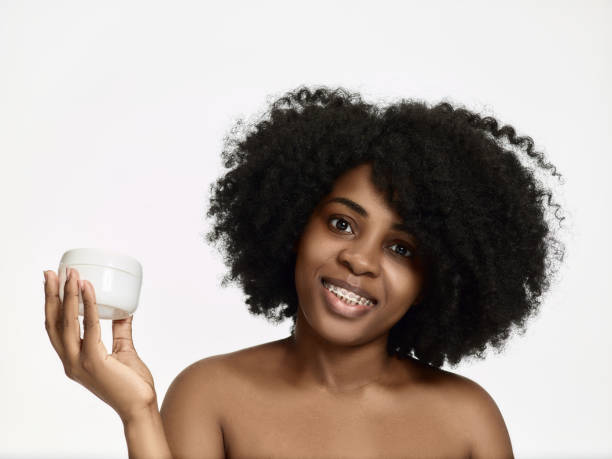 istock Beautiful black african model with flawless skin smooth complexion applying moisturiser face cream to her cheek 1138430830