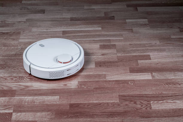 istock White robotic vacuum cleaner runs on laminate floor. Robot hoover controlled by voice commands for direct cleaning. Modern smart appliance for cleaning house 1138431628