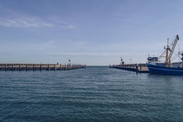 view of breakwater and part of moored fishing trawler in front of open sea in oudeschild port - oudeschild imagens e fotografias de stock