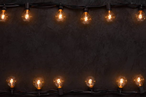 istock Light bulbs retro garland on dark black wall 1138435268