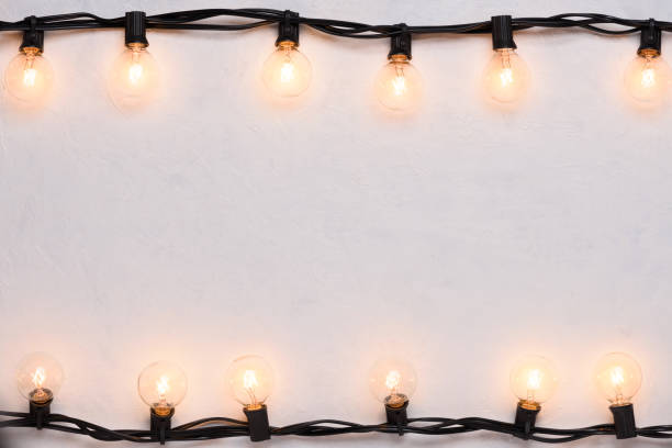 Garlands of glowing warm lamps on white wall