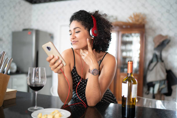 istock Woman drinking wine while listening her favorite on smart phone 1138438149