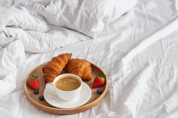 istock Coffee and croissants on the white bedsheets close-up 1138438591