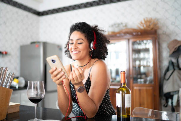 istock Woman drinking wine while listening her favorite on smart phone 1138440301