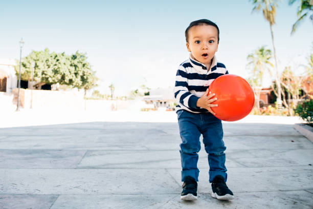 niño jugando pelota en un parque - child discovery surprise playing fotografías e imágenes de stock