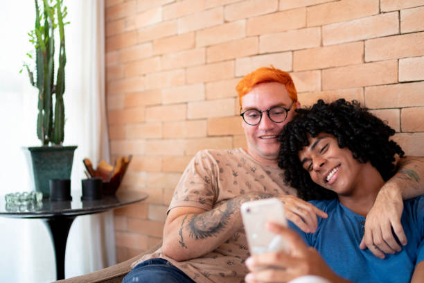coppia omosessuale su un cellulare usato a casa - homosexual homosexual couple black ethnic foto e immagini stock