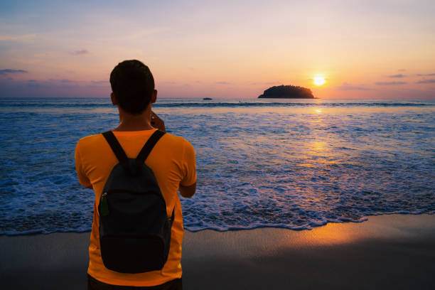 istock Man using smartphone shooting image on sea sunset or sunrise in twilight 1138442027