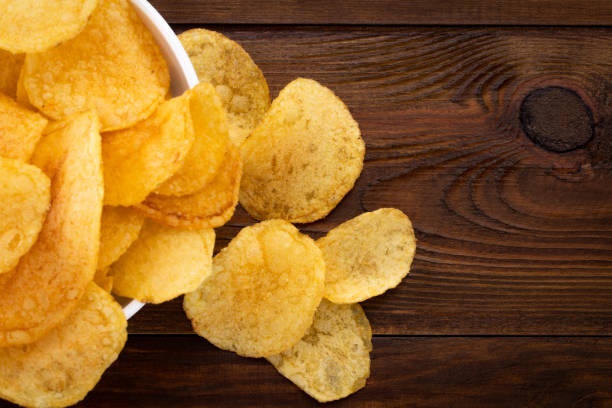 istock Crispy potato chips in bowl on wooden background, top view 1138443407