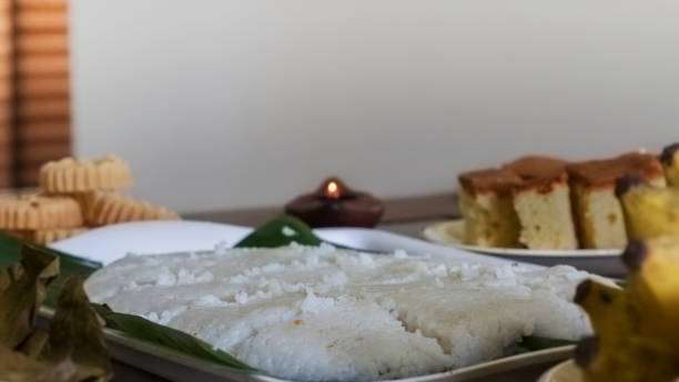 Plate of Milk Rice (Kiribath) along with a lit oil lamp, Kokis, Cake and Banana in the background and foreground. stock photo