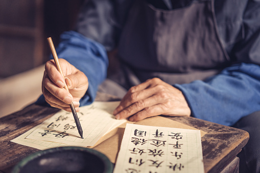 Chinese senior man writing chinese calligraphy on paper