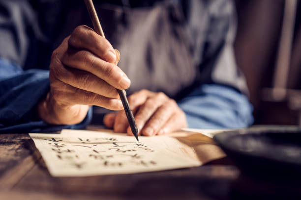 Chinese senior man writing chinese calligraphy on paper