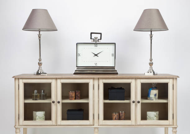 istock Glass fronted sideboard and ornaments with lamps and a large clock on a white background 1138444513