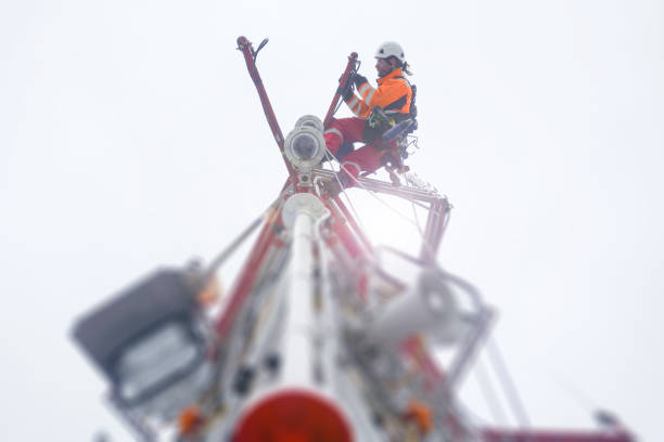 Rope access technician climbing on the tower - antenna with hooks and looking down stock photo